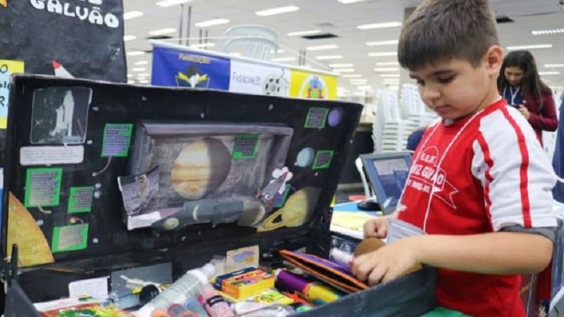 Foto de Pedro mexendo em sua maleta de experimentos
