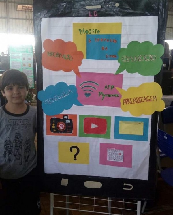 Foto de Pedro ao lado de um cartaz sobre o app que estava desenvolvendo para a escola