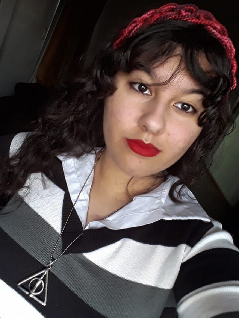 Foto de Thais, séria, com um colar alusivo à saga Harry Potter