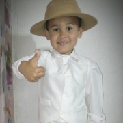 Foto de um menino fazendo sinal de positivo com o dedo, vestido com pilchao