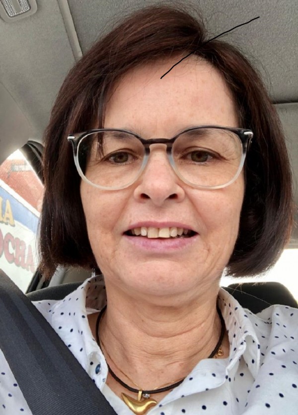 Foto da oncologista Elisabeth, sorrindo, de óculos, em um carro