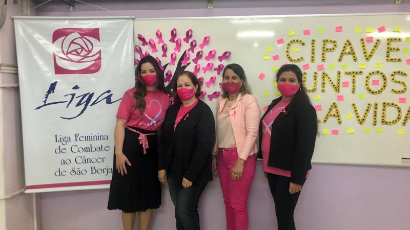 Foto onde aparecem quatro mulheres ao lado de um banner da Liga Feminina de Combate ao Câncer de São Borja