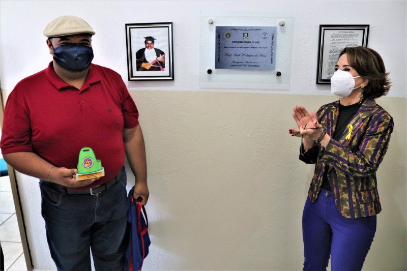 Secretária Raquel Teixeira e o filho da professora Sueli, Cristiano Rodrigues, em ato de descerramento da placa inaugural