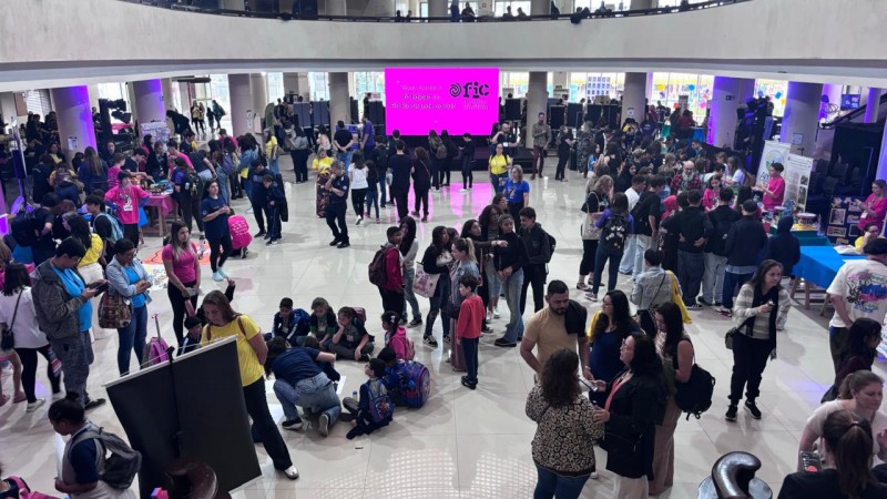 Foto do salão principal do Instituto Federal de Educação, mostrando um saguão amplo com diversas pessoas circulando entre estandes de estudantes. 