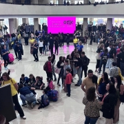 Foto do salão principal do Instituto Federal de Educação, mostrando um saguão amplo com diversas pessoas circulando entre estandes de estudantes. 