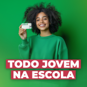 Imagem com fundo verde em degradê. Uma jovem sorridente de moletom verde segura um cartão. Texto em destaque: "TODO JOVEM NA ESCOLA", em branco sobre fundo vermelho. No canto inferior direito, logo do Governo do RS e da Secretaria da Educação.