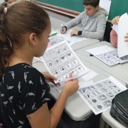Estudantes em sala de aula participam de atividade com recorte de figuras impressas em folhas