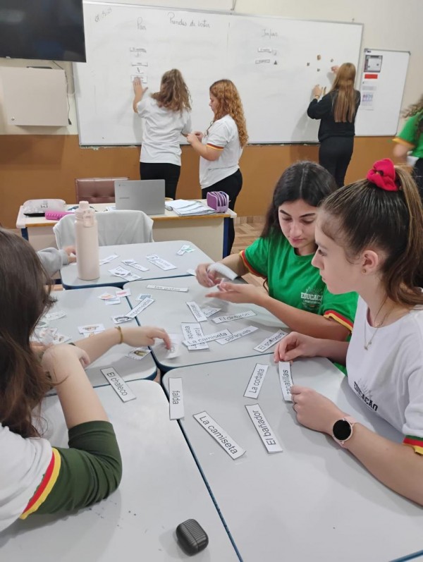 Estudantes em sala de aula participam de atividade com cartões de palavras em espanhol.