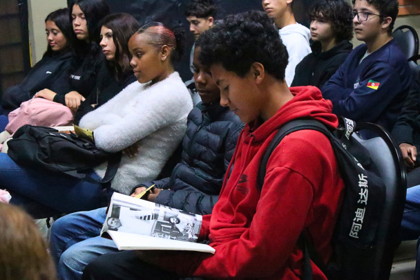 Estudante manuseia livro com o roteiro de um filme. 