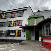 Pr&eacute;dio de tr&ecirc;s andares com v&aacute;rias janelas e pintura nova, com uma grande porta branca na entrada. Acima, letreiro "Instituto de Educa&ccedil;&atilde;o Assis Brasil"

