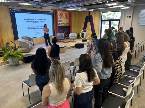 Palestra da formação, com mulheres na platéia em pé ouvindo palestrante