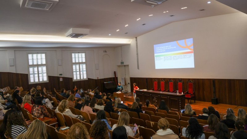 Imagem mostra audit&oacute;rio onde a forma&ccedil;&atilde;o estava acontecendo. V&aacute;rias pessoas sentadas na plat&eacute;ia enquanto duas mulheres no palco ministram a forma&ccedil;&atilde;o. 